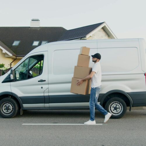 Delivery guy carring boxes past van