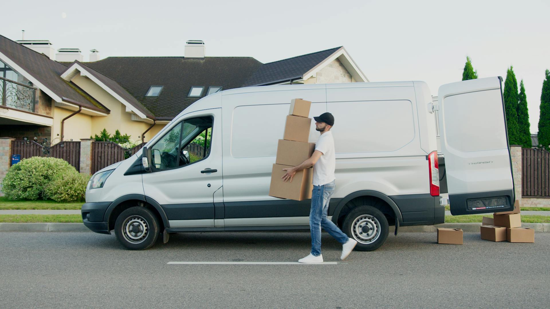 Delivery guy carring boxes past van