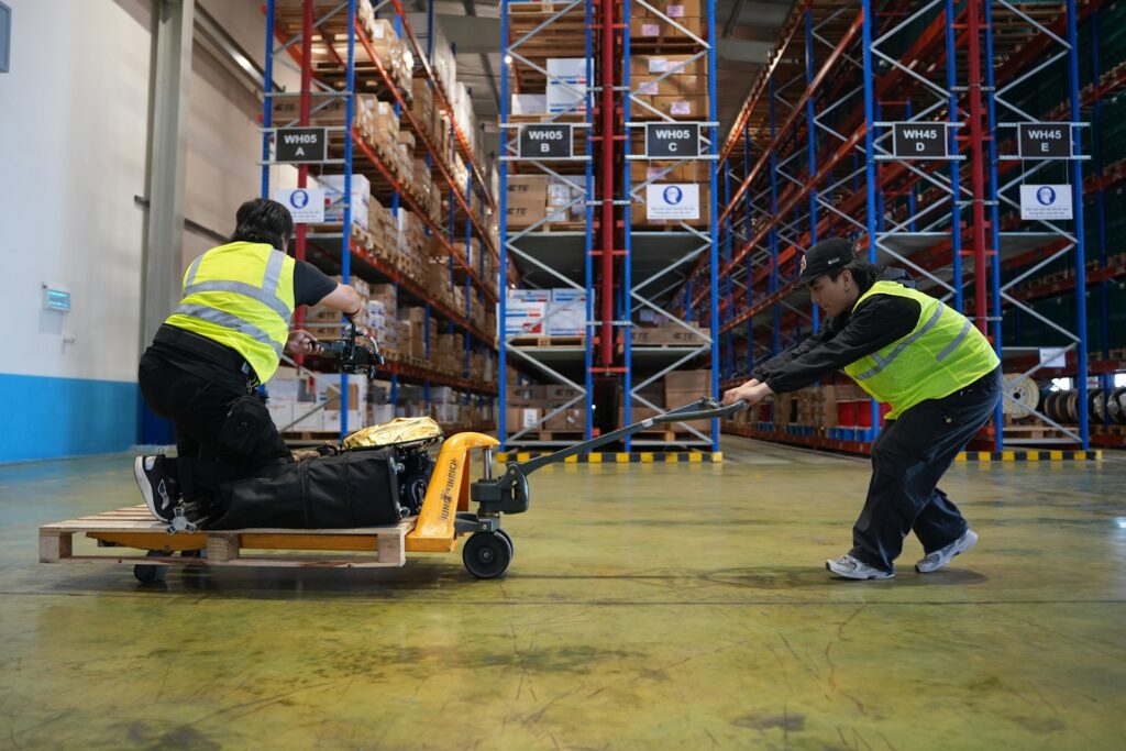 two warehouse workers pulling equipment