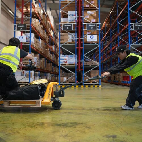 two warehouse workers pulling equipment